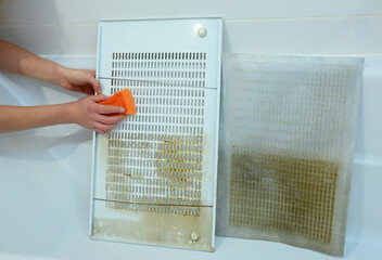 Cleaning a cooker hood filter from fat. A close-up of cleaning a greasy kitchen hood, range hood filters, grates with a sponge. - obrazy, fototapety, plakaty