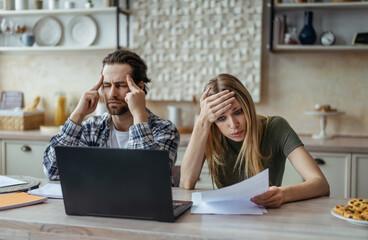 Sad shocked millennial caucasian husband with stubble and wife pay bills, taxes and have problems...