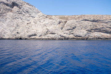 Folegandros island, Vorina bay, Cyclades, Greece. High cliff, Aegean ripple sea, clear blue sky.