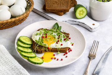 Sandwich with scrambled eggs, microgreens and pink pepper on a plate. Delicious and healthy snack