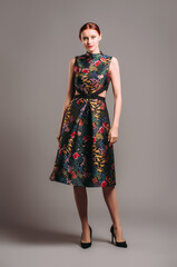 Cut out waist midi dress in floral embroidery with black high heels. Ginger lady posing in studio....