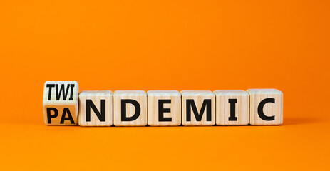 Covid-19 pandemic or twindemic symbol. Turned wooden cubes and changed the concept word pandemic to twindemic. Beautiful orange background copy space. Medical Covid-19 pandemic or twindemic concept.