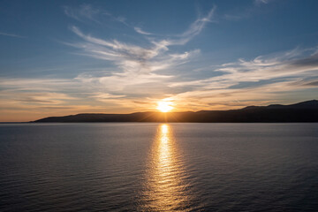 Sunset over Koufonisia island silhouette, Cyclades, Greece. Sunbeam paints gold Aegean calm sea.