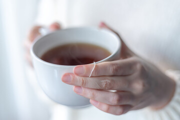 close up of woman's hands holding a big white cup of hot tea