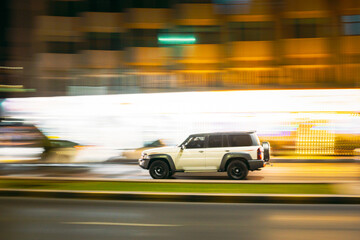Fototapeta na wymiar White SUV Car Fast Moving In City Street. Motion Blur Background.