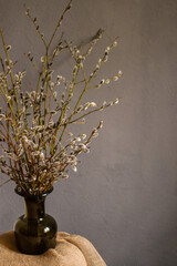 willow twigs in a green vase on a gray background