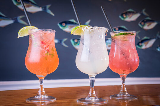 Three Mixed Drink Cocktails in front of a Fish Background on a Wooden Table