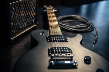 Naklejka na ściany i meble Close-up, black electric guitar on a dark background.