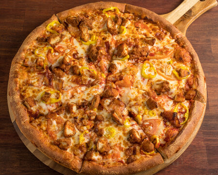 Buffalo Chicken Pizza with Yellow Banana Peppers on a Wooden table