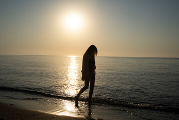 Fototapeta premium Girl walking along the beach at dawn