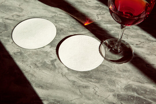 Coasters thin white round with wine glass under sunlight