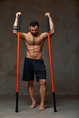 A ninja man holds on to a fighting stick and attacks close-up on gray studio background