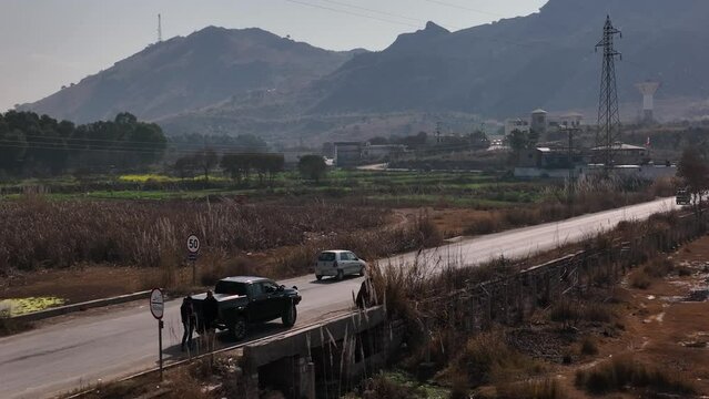 Aerial Circle Dolly View Of Parked SUV Beside Rural Road In Kallar Kahar In Pakistan. Slow Motion