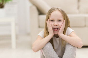 Photo of small blonde girl showing tongue.