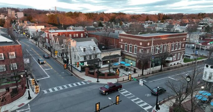 Main Street USA small town square, red light intersection. Golden hour light by aerial as cars and truck drive through town. Aerial establishing shot.
