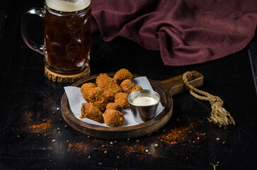 Hot cheese balls with glass of beer on wooden table