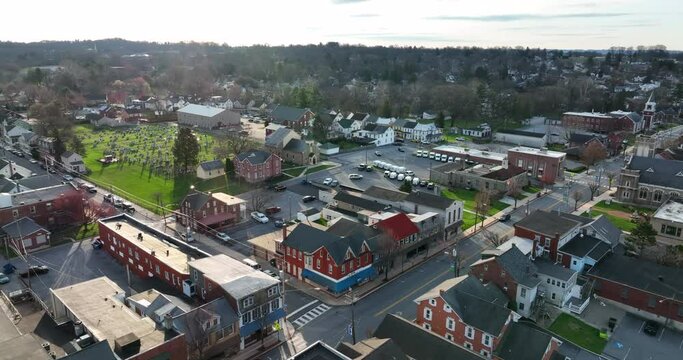 Town in America aerial establishing shot at sunrise. Light reflects on cemetery gravestones. America lifestyle shot.