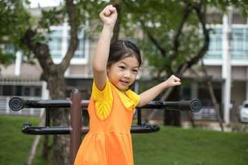 Asian happy girl with orange dress is playing in the playground.