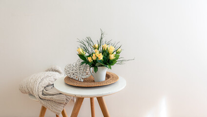Home composition with flowers in a vase in the interior of a white room.