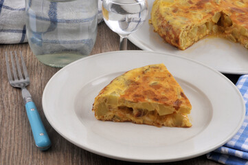Part d'omelette espagnole servie dans une assiette avec un verre d'eau