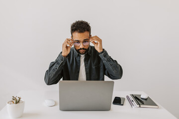 Cheerful handsome black skinned guy wearing eyeglasses before starting type blog for internet...