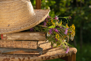 Old books, straw hat, wildflowers. Summer rest. Summer in the countryside.