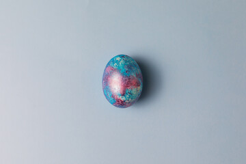 Easter egg. Dyed Easter egg with marble stone effect pink and blue color on light blue background. Top view. Happy Easter concept.