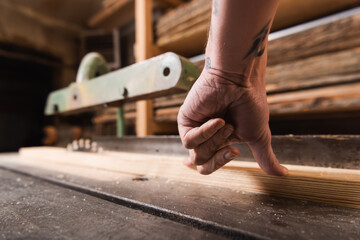 cropped view of carpenter sawing wooden plank on circular saw.