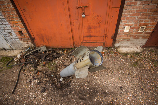 Close-up view stock image of real unexploded military missile, torpedo or shell stuck in ground near doors of garages outdoors. Moments of dreadful war of Russia against Ukraine in 2022