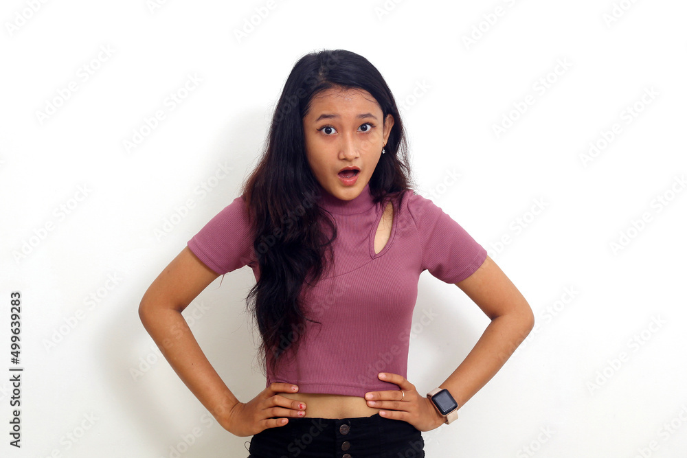 Wall mural asian girl with shocked face holding stomach with mouth open isolated on white background