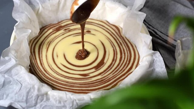 Making marble or zebra cake. Pouring chocolate and white dough step by step into the baking pan to prepare the striped dessert