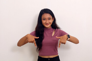 Asian girl smiling stand makes gesture two fingers pointing down presenting and looking to camera