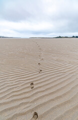 Sand background with waves of the low sea in Lugo, Galicia, Spain and foot prints