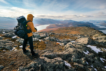 Male hiker overlooking epic view of vast arctic landscape of Stora Sjofallet National Park, Sweden,...