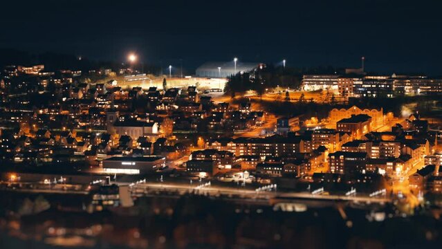 Timelapse of the Narvik city at night. Brightly lit streets, cars moving around. Dark sea in the background.