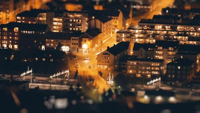 A train passes the station in the city of Narvik at night. Timelapse tilt-shift video.