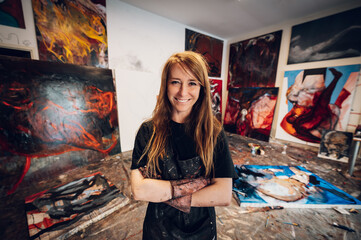 Young redhead woman painter standing by her art masterpiece on a big canvas