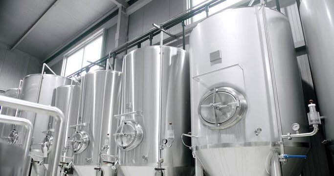 Huge stainless vats in a brewery. Equipment for beer fermentation. Brewing equipment. Factory, brewery concept. Large reservoirs, tanks and pipes with manometers in private microbrewery.