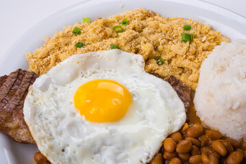 Steak with egg on top, rice, farofa and beans. Brazilian food.
