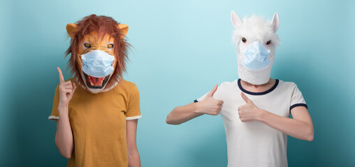 Young woman wearing lion and protection medical mask pointing up with index finger, and in alpaca...