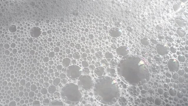 Soft liquid soapy foam on water surface as texture or background, video 4k resolution
