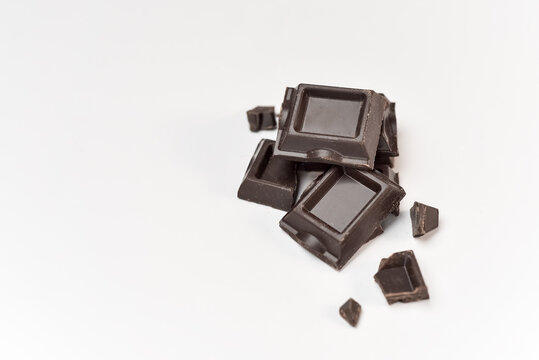 Dark bitter sweet chocolate pieces on white isolated background