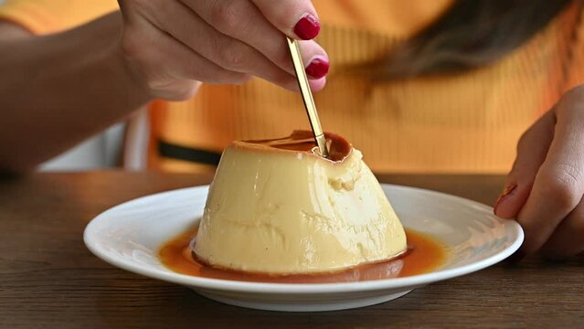 Woman cutting a pudding for eat by spoon. Pudding is a popular dessert and snack. It tastes sweet, and comes in many flavors.