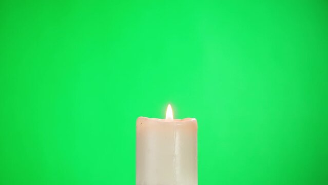 Burning wax candle on green chroma key background. Fire flame candlelight close-up.