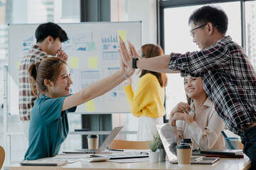 Groups of startup company employees are in the conference room, they are clapping hands to express their joy after looking at the company's sales and profitability. Startup company concept.