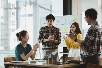 Groups of startup company employees are in the conference room, they are clapping hands to express their joy after looking at the company's sales and profitability. Startup company concept.