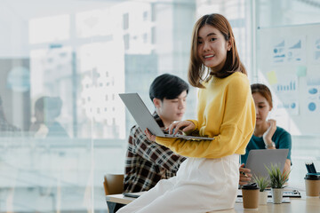 Obraz premium Asian woman head of department sitting in startup company conference room, group of people meeting to plan events and brainstorm ideas to grow the company. Concept of female executives, female leaders