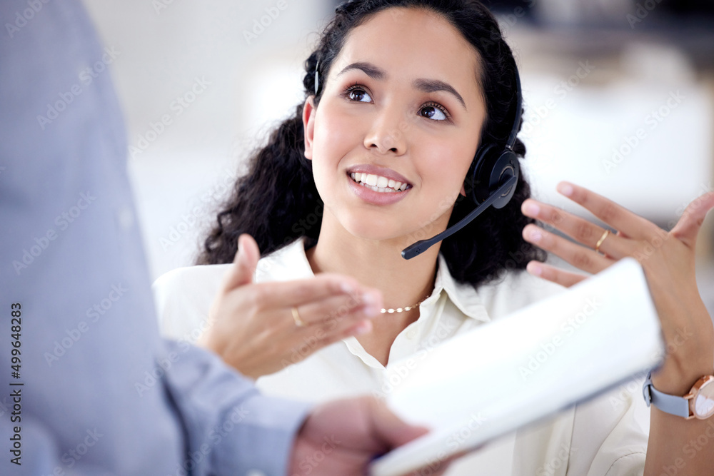 Poster Sharing her input to find the best solution. Shot of a young call centre agent talking to a colleague in an office.