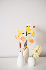 Mixed spring flowers in modern bud vases against white