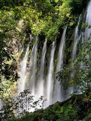 Group of waterfalls accompanied by a rainbow on the cliff.